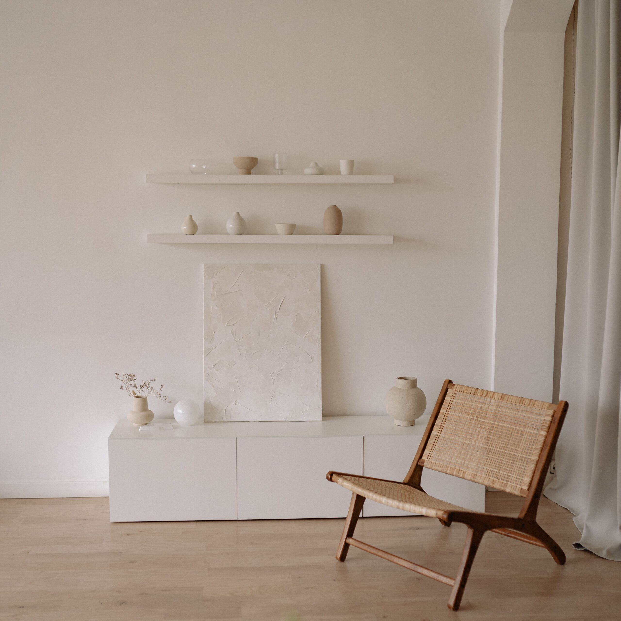 Elegant minimalist living room featuring a wicker chair and neutral decor elements.